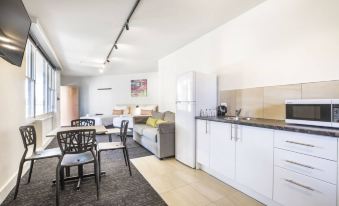 a modern kitchen and dining area with a couch , table , chairs , and a refrigerator at Nightcap at Glengala Hotel