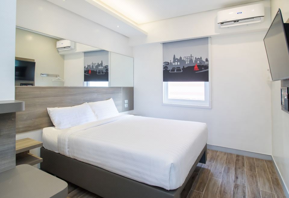 a modern hotel room with a white bed , wooden flooring , and an air conditioner on the wall at Red Planet Manila Bay