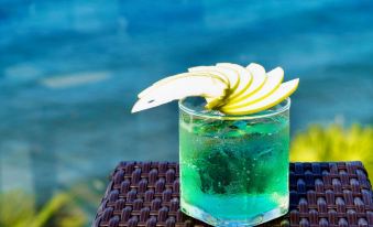 a glass of green drink with a slice of lemon and a straw on a table at Seashells Phu Quoc Hotel & Spa