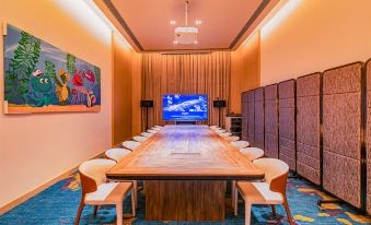 A spacious conference room with a long table and chairs is situated facing a wall-mounted TV at Chimelong Spaceship Hotel