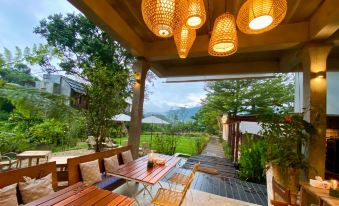 a wooden patio with a table and chairs , surrounded by a lush garden and mountains in the background at Proud Phu Fah Hip & Green Resort