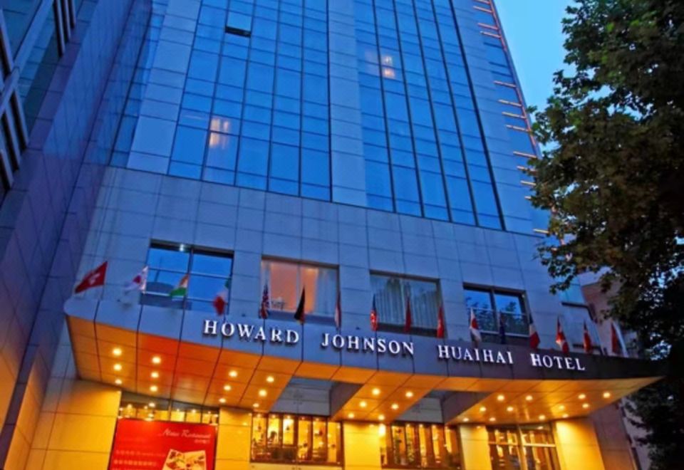 In Japan, there is a large building with a front view and an illuminated sign on its side at Howard Johnson Huaihai Hotel Shanghai