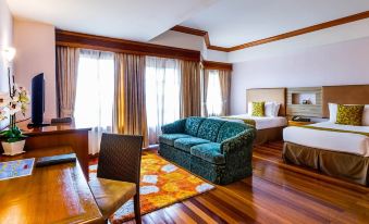 a hotel room with two beds , a couch , and a dining table , all situated in a spacious living area at Thistle Port Dickson Resort