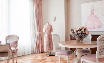 a room with a pink dress hanging on a mannequin , surrounded by white curtains and wooden furniture at The Langham Melbourne