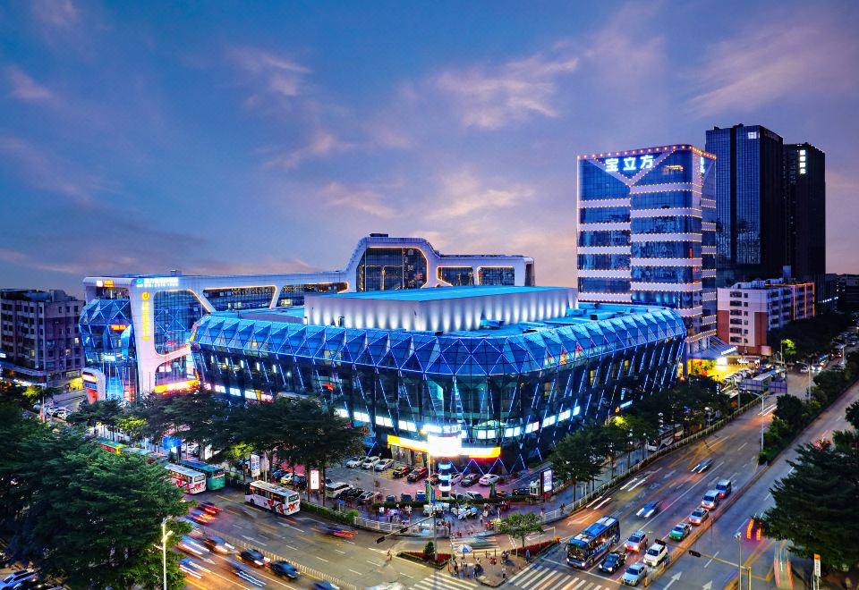 A large, multi-story building with a central outdoor view is illuminated at Gems Cube International Hotel