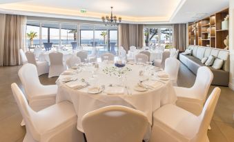 a well - decorated dining room with white tablecloths and chairs set up for a formal event at DoubleTree by Hilton Malta