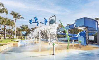 a water park with various water features , such as fountains and slides , for children to play in at NRMA Merimbula Beach Holiday Resort