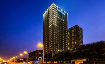 At night, a large, illuminated clock adorns a city building with numerous windows at LEFUQIANG BOYUE HOTEL
