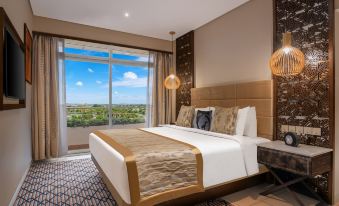 a luxurious bedroom with a large bed and a view of the city outside the window at Neelkanth Sarovar Premiere