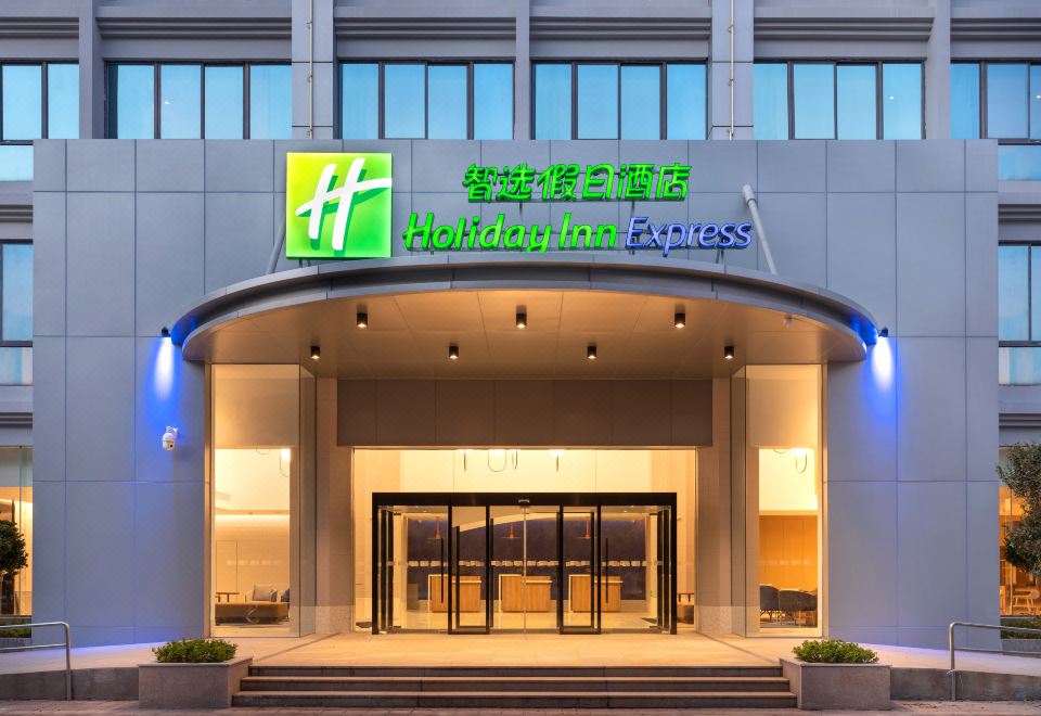 "The front entrance of a hotel is adorned with a sign that says ""welcome"" and features the hotel's logo" at Holiday Inn Express Xiamen Tongan