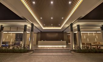 a modern hotel lobby with a marble floor , white columns , and a reception desk under a wooden ceiling at Mambruk Hotel & Convention