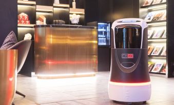 A robot stands on the floor next to another machine with lights in front at CITIGO hotel, Sanlitun, Beijing