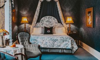 a lavishly decorated bedroom with a canopy bed , blue curtains , and a black and white floral comforter at Prince of Wales