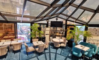 a modern cafe with a glass roof , featuring various seating options and potted plants on the tables at Hotel Old Town