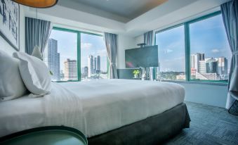 a bedroom with a large bed , television , and floor - to - ceiling windows overlooking a cityscape at Z Hotel