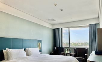 The bedroom features large windows and a bed in the center, with an adjacent easy chair at Chunguang Hotel