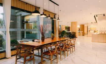 elegant dining space featuring large windows, a wooden table, and chairs arranged in the center at Shanghai JOYFUL YARD Hotel (Shanghai Pudong Airport Store)