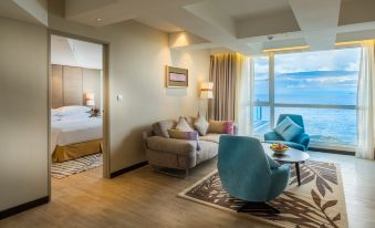 a modern living room with a couch , chair , and coffee table in front of a large window overlooking the ocean at DoubleTree Resort by Hilton Hotel Penang