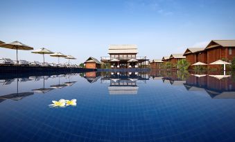 a large outdoor pool surrounded by a resort , with umbrellas and lounge chairs placed around it at Duyong Marina & Resort
