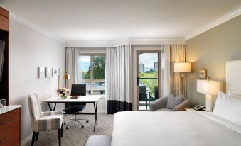 a hotel room with a bed , desk , and chairs , as well as a balcony overlooking the city at Hotel Grand Pacific