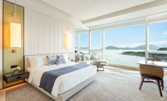 The bedroom features large ocean-facing windows and a white bed at The Fullerton Ocean Park Hotel Hong Kong