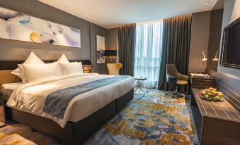 a modern hotel room with a large bed , blue and yellow floral rug , and a view of the city at Ames Hotel