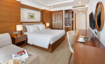 a luxurious hotel room with a king - sized bed , a desk , and a tv , all arranged in a comfortable atmosphere at Paris Deli Danang Beach Hotel