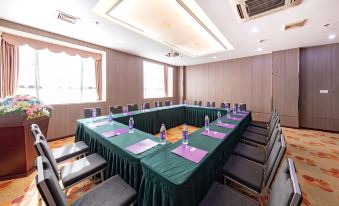 a large conference room with multiple tables , chairs , and green tablecloths arranged in a semicircle formation at AQUEEN HOTEL