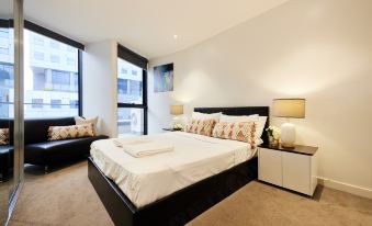 a spacious bedroom with a large bed , a couch , and a tv . the room is well - organized and clean at Arrow on Swanston