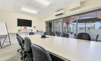 a conference room with a long table , chairs , and a tv screen on the wall at Argus Hotel Darwin