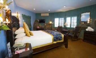 a luxurious bedroom with a king - sized bed , a flat - screen tv mounted on the wall , and a comfortable chair at Madonna Inn