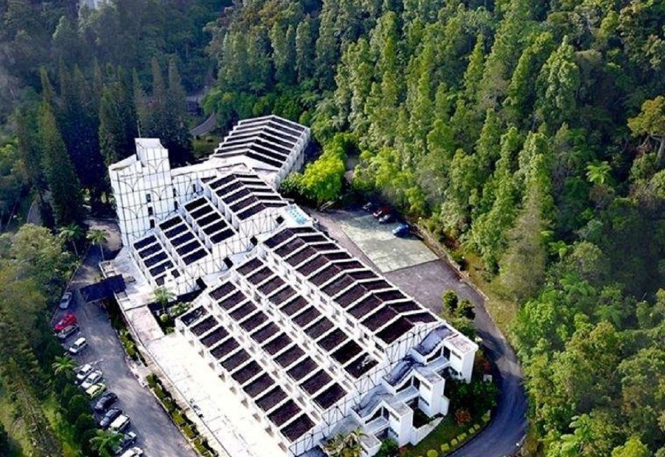 an aerial view of a large white building surrounded by trees , with a parking lot in front at Shahzan Inn Fraser's Hill