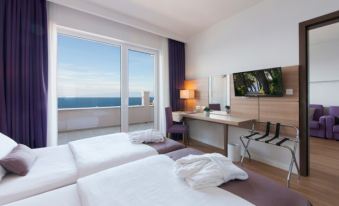 a hotel room with two twin beds and a flat - screen tv mounted on the wall at Vitality Hotel Punta