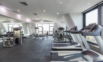 a gym with treadmills , stationary bikes , and other exercise equipment arranged in a spacious room at SureStay Hotel by Best Western Vientiane
