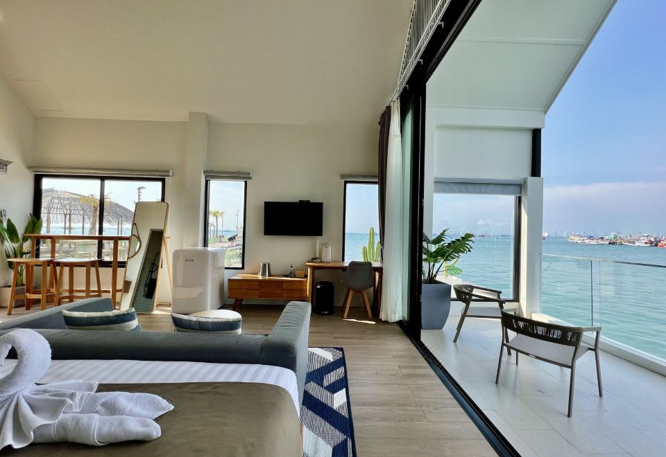 a bedroom with a bed , a tv , and a balcony overlooking the ocean at a luxury resort at Baan Tah on the Sea