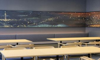 a modern classroom with a large cityscape mural on the wall , and several rows of tables and chairs set up for the students at Hotel Torifito Hakata Gion