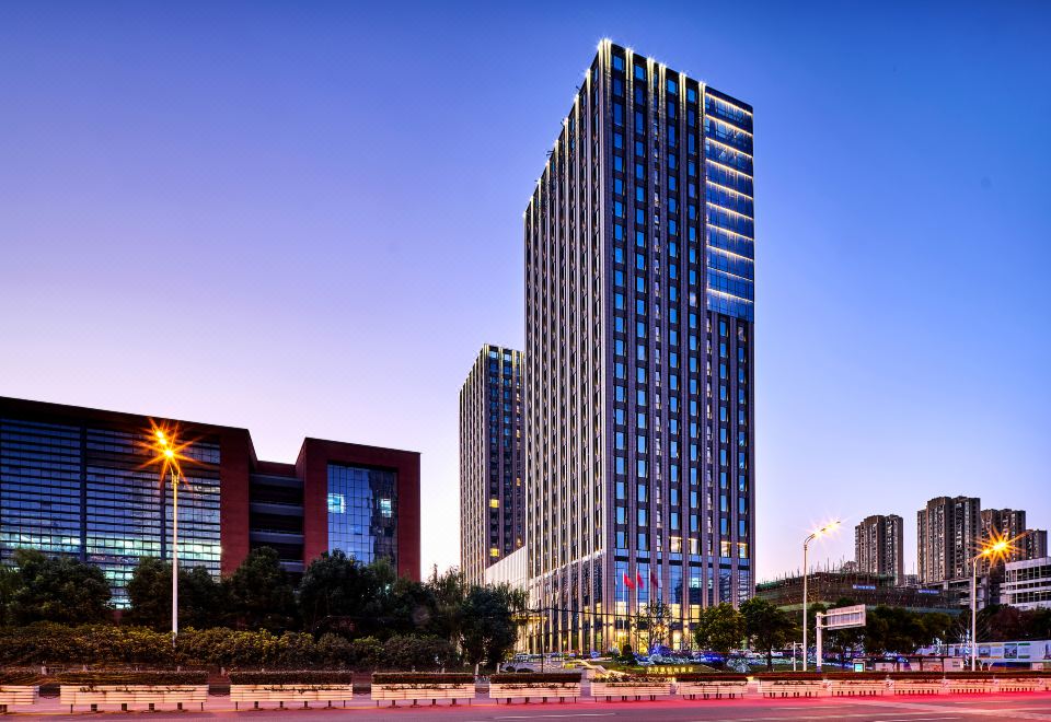 A city building offers a nighttime outside view, with a rooftop bar for guests to enjoy drinks and admire the city skyline at LEFUQIANG BOYUE HOTEL