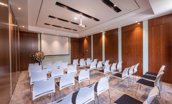 a conference room set up for a meeting , with chairs arranged in rows and a projector on the wall at Suisse Apartment Hotel Suzhou Jinji Lake Expo Center