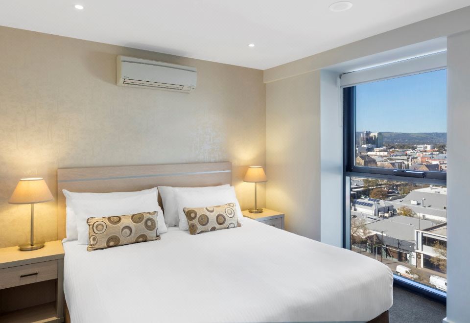 a large bed with white sheets and two decorative pillows is situated in a room with a window at IStay Precinct Adelaide
