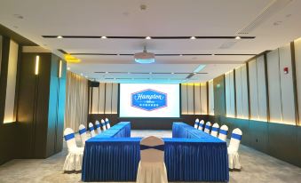 A spacious event room is arranged with blue chairs and white tablecloths at Hampton by Hilton Shenzhen North Station