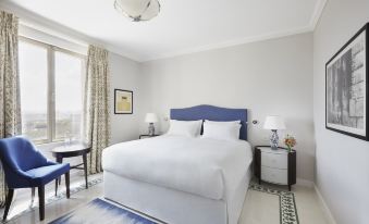 a large white bed with a blue headboard is in the center of a room at The Phoenicia Malta
