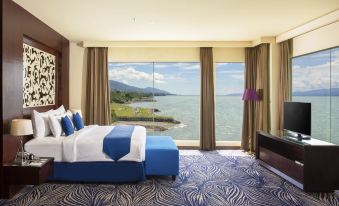 a luxurious bedroom with a large window overlooking a body of water , creating a serene and tranquil atmosphere at Swiss-Belhotel Silae Palu