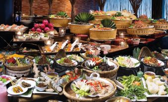 a large buffet table filled with a variety of food , including vegetables , fruits , and meats at Hotel Maya Kuala Lumpur City Centre
