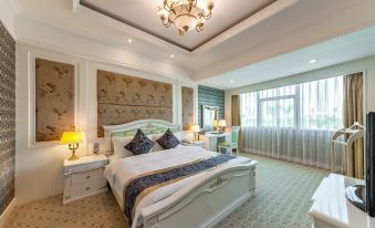 a large bed with a white headboard and white linens is in a room with a chandelier , lamps , and a window at Swan Hotel