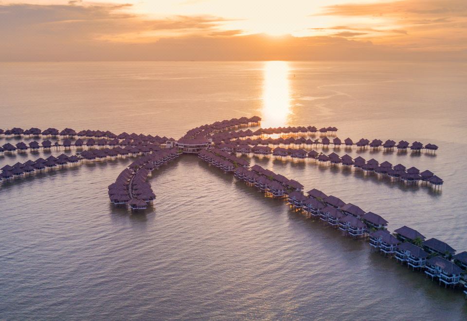 aerial view of a large body of water with multiple floating wooden houses on it , surrounded by the sun setting in the distance at Avani Sepang Goldcoast Resort
