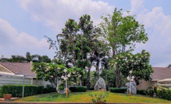 a beautiful garden with trees , flowers , and a statue is shown in front of a house at OYO 926 Sydney Resort