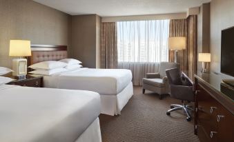 a hotel room with two twin beds , a chair , and a window overlooking the city at Sheraton Parkway Toronto North Hotel & Suites