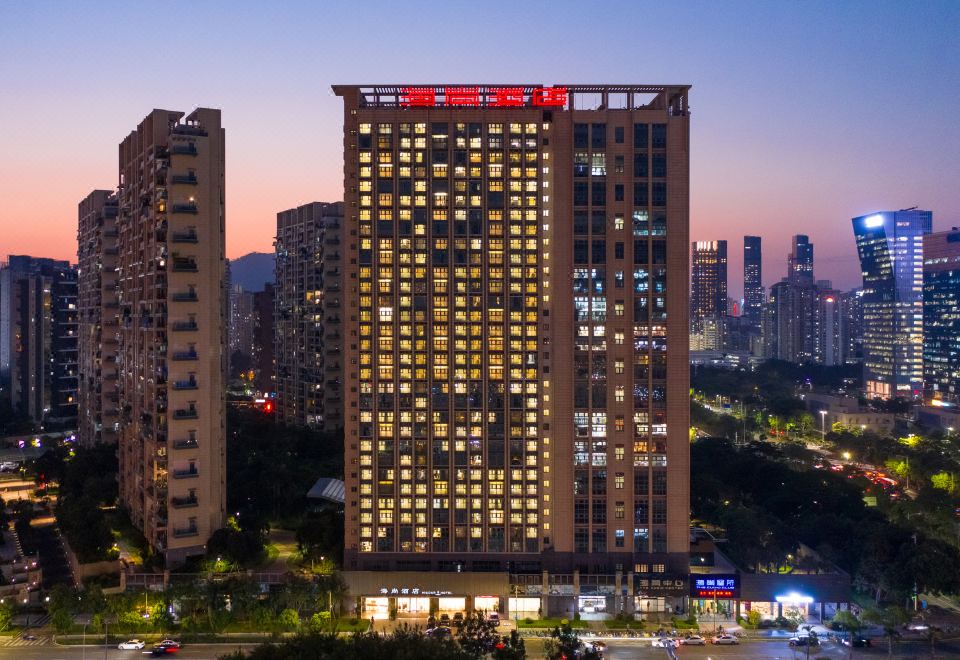 At night, a well-lit large building stands among other buildings in the city at Hisoar Hotel
