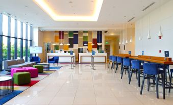 a modern , well - lit hotel lobby with multiple dining tables and chairs arranged for guests to sit and enjoy their meal at Park Inn by Radisson North Edsa