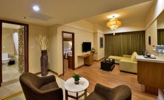 a well - furnished living room with a couch , two chairs , a television , and a dining table at Pearl View Hotel Prai, Penang